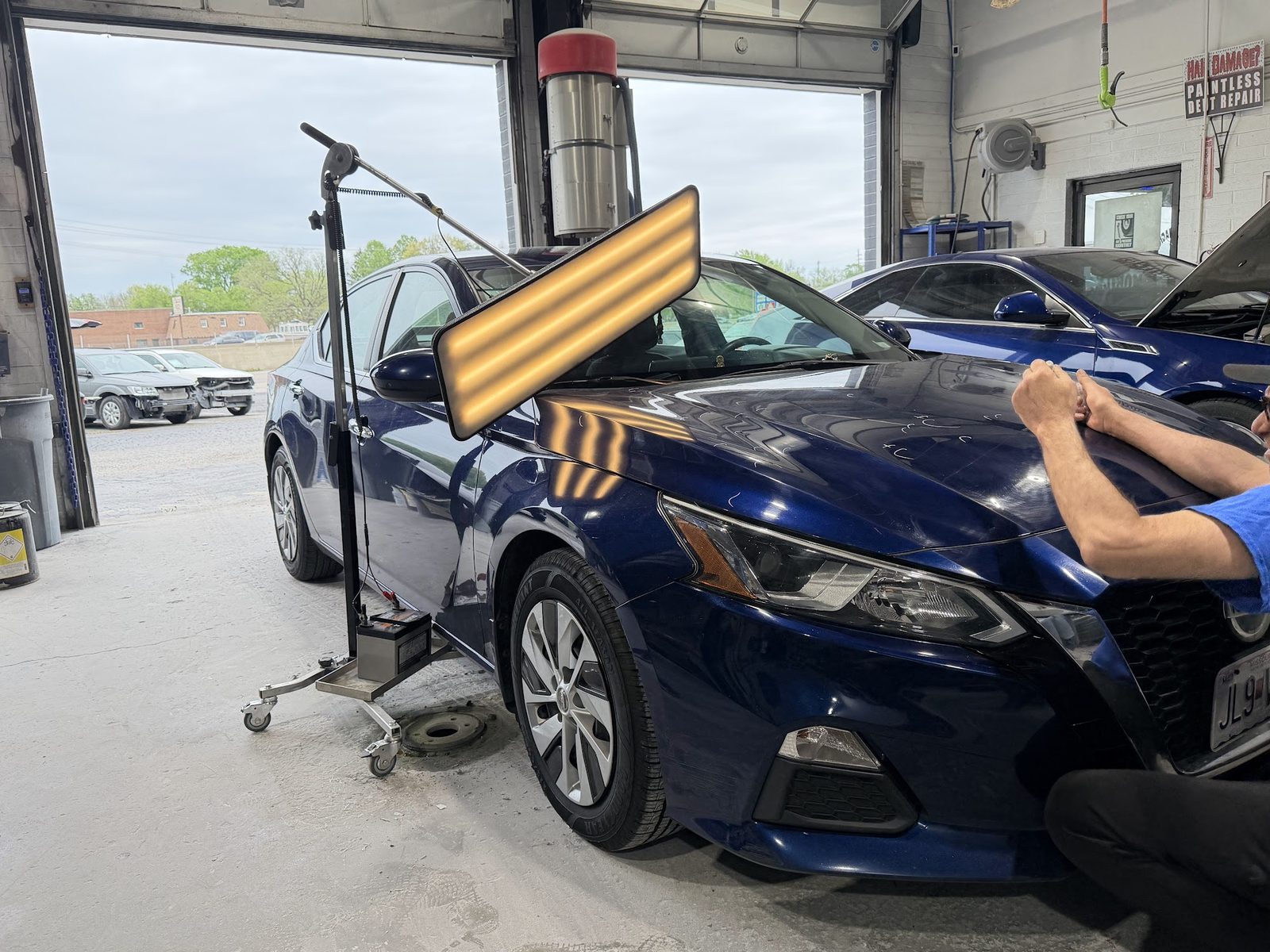 Paintless dent repair in progress on a vehicle inside the Mobile Magic Auto Body shop in St. Peters, MO